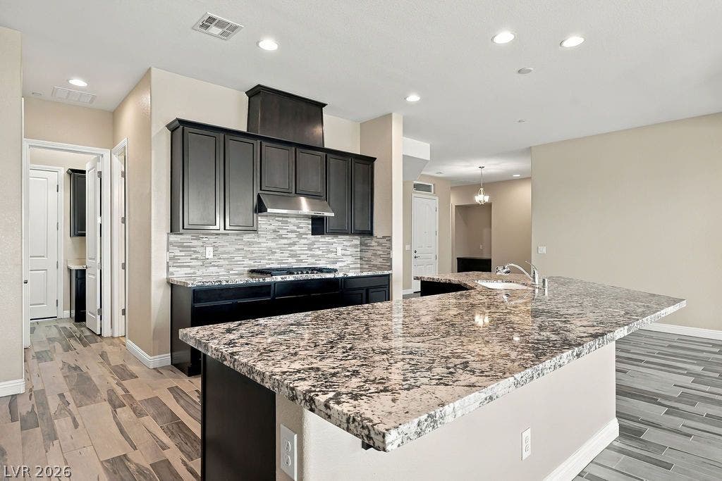 286 Lindura Court, Las Vegas, NV 89138 Granite countertops and dark cabinetry anchor this open culinary space under recessed lighting.