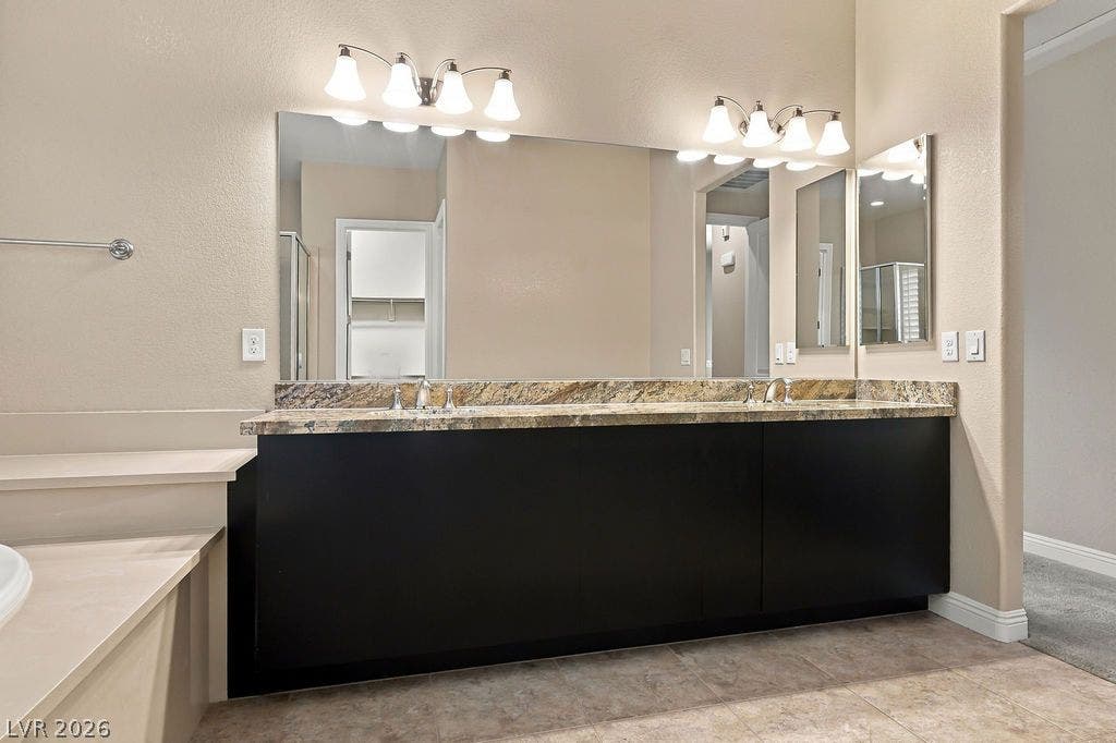 286 Lindura Court, Las Vegas, NV 89138 A spacious double vanity features granite countertops and sleek dark cabinetry beneath bright lighting.