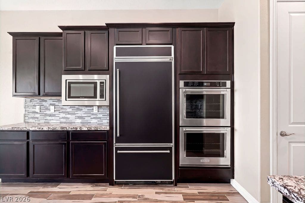 286 Lindura Court, Las Vegas, NV 89138 Rich dark wood cabinetry stands out against tile flooring and integrated high-end kitchen appliances.