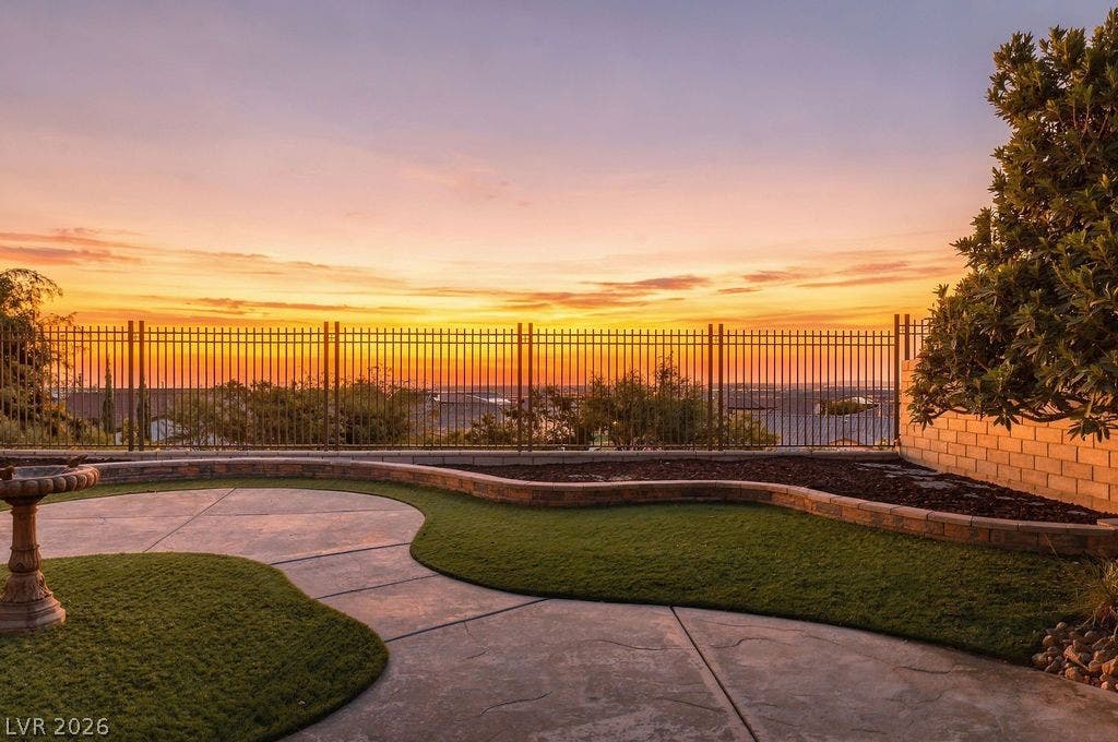 286 Lindura Court, Las Vegas, NV 89138 Gated yard area overlooks neighborhood vistas under golden evening skies with a Las Vegas strip view.