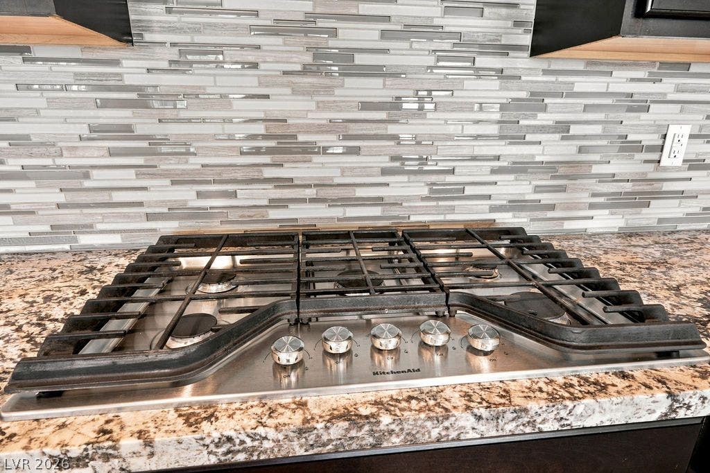 286 Lindura Court, Las Vegas, NV 89138 A modern built-in gas cooktop sits flush within polished granite countertops beneath tiled walls.