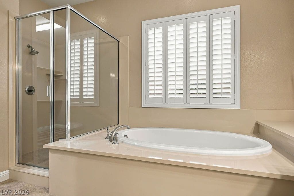 286 Lindura Court, Las Vegas, NV 89138 An oval soaking tub rests beneath bright plantation shutters next to a glass shower.