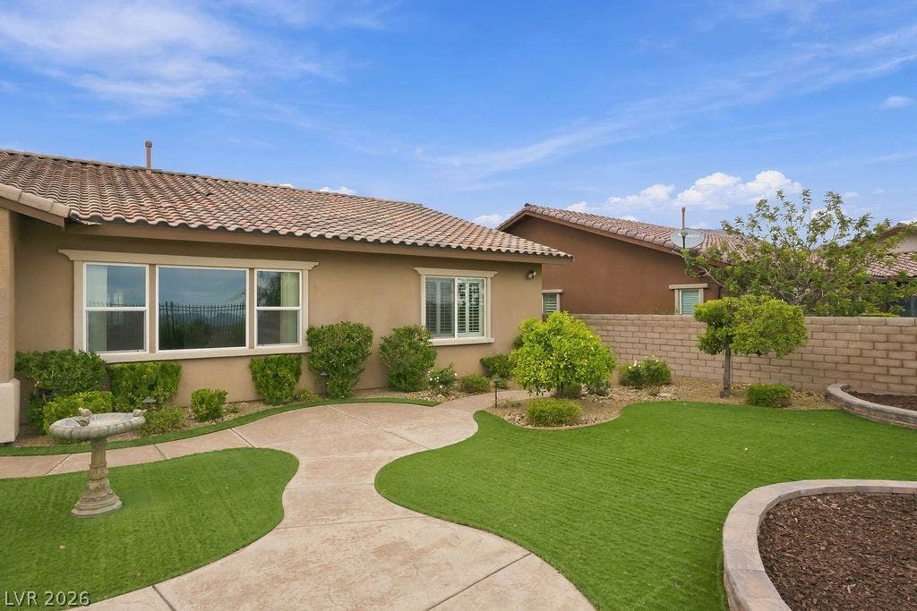 286 Lindura Court, Las Vegas, NV 89138 A curved concrete walkway winds through the landscaped backyard under a clear blue sky.