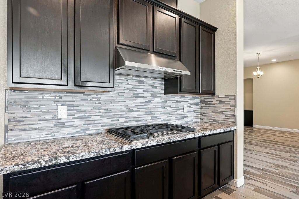 286 Lindura Court, Las Vegas, NV 89138 Rich dark cabinetry pairs beautifully with stone countertops and a modern tile backsplash.