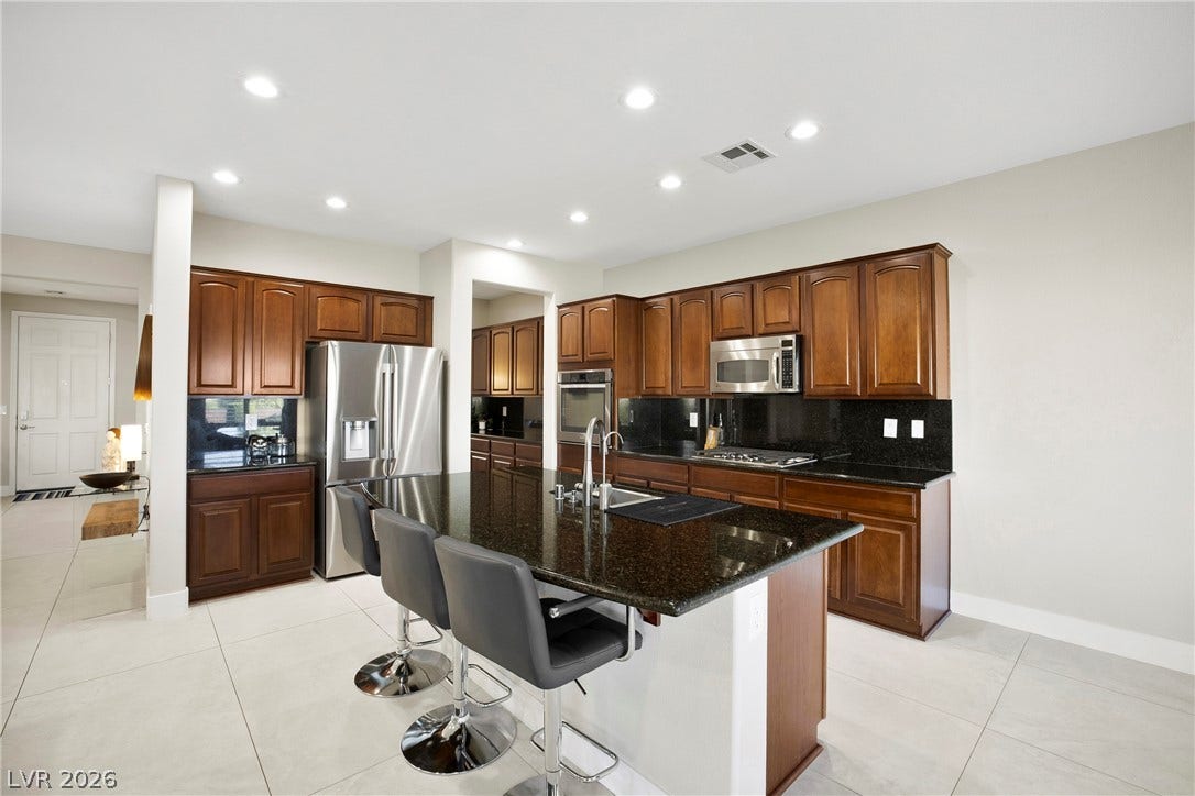 2432 Anderson Park Drive, Henderson, NV 89044 Rich wood cabinetry and a dark stone island anchor this open culinary space.