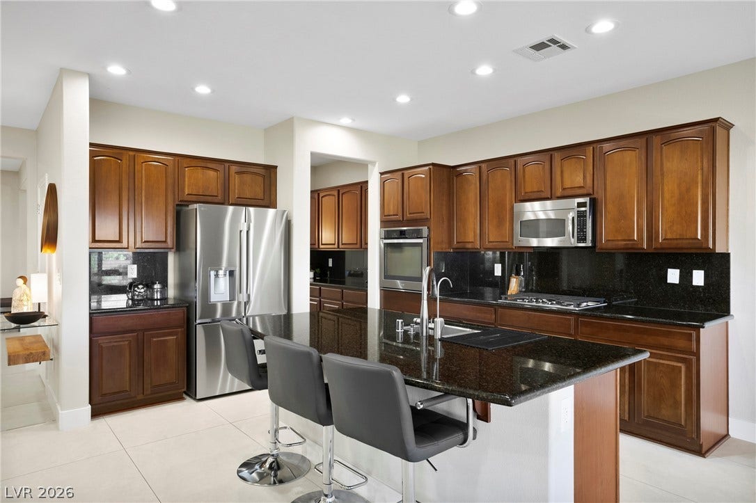 2432 Anderson Park Drive, Henderson, NV 89044 Rich wood cabinetry and sleek stone countertops ground this open, modern kitchen design.