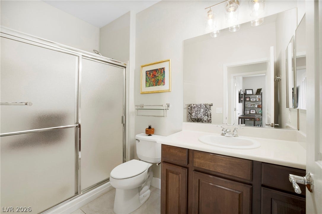 2432 Anderson Park Drive, Henderson, NV 89044 Rich wood cabinetry anchors the vanity in this well-appointed bathroom featuring a walk-in shower.