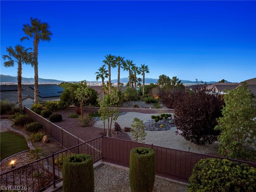 2432 Anderson Park Drive, Henderson, NV 89044 Distant mountains frame the horizon beyond a meticulously landscaped yard with palm trees.