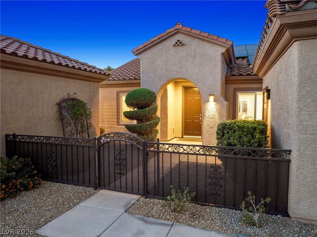 2432 Anderson Park Drive, Henderson, NV 89044 An arched stucco entryway opens beyond a gated courtyard with Mediterranean tile roofing.