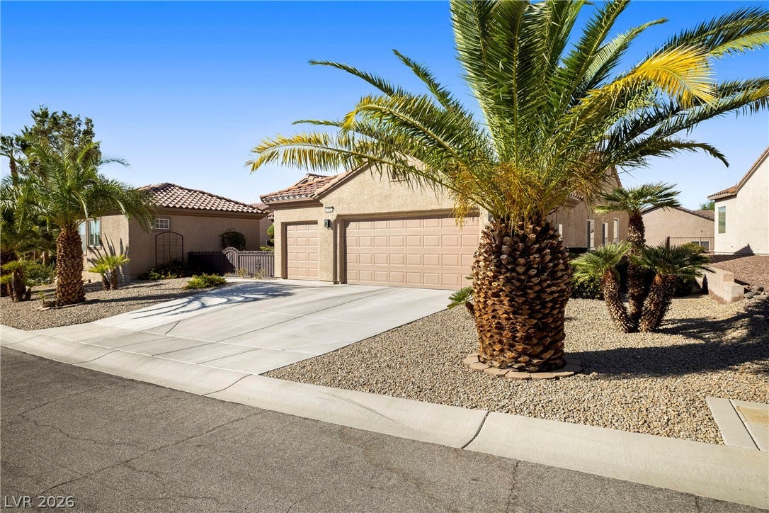 2432 Anderson Park Drive, Henderson, NV 89044 Palm trees frame the concrete driveway leading to a spacious three-car garage and tiled roof.