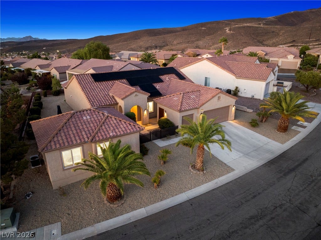 2432 Anderson Park Drive, Henderson, NV 89044 Sunset skies frame this desert home featuring tile roofing and solar panels against mountain backdrops.