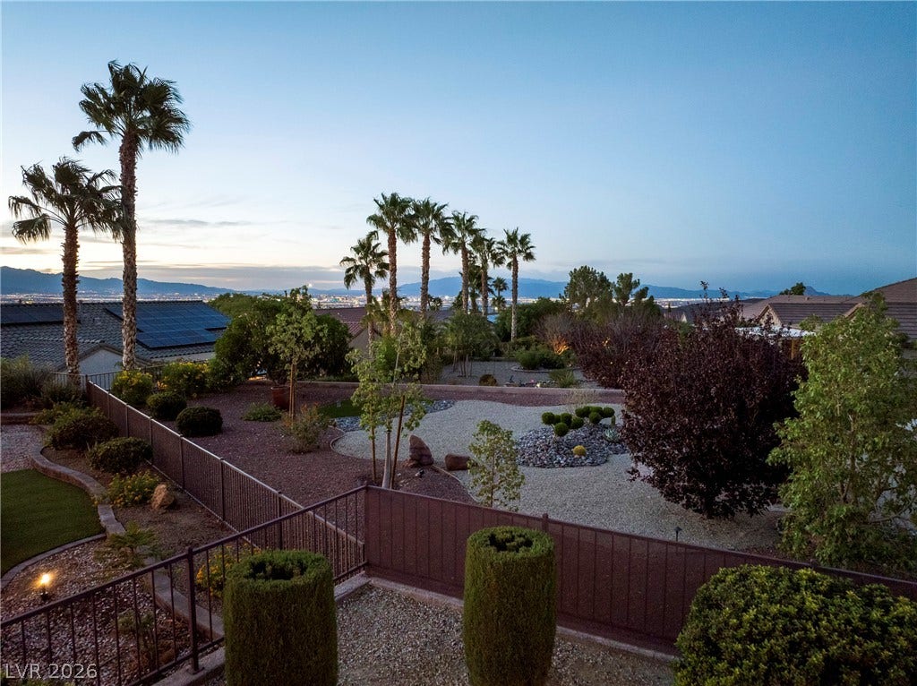 2432 Anderson Park Drive, Henderson, NV 89044 Distant city and mountain views frame a desert landscaped backyard with palm trees.
