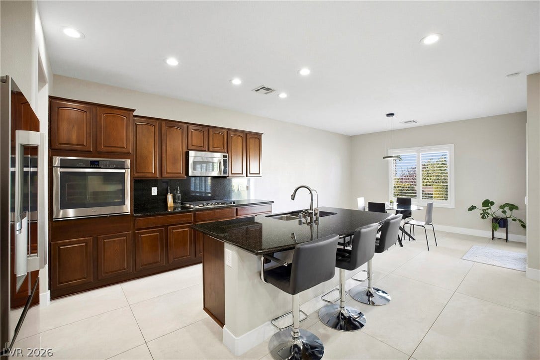 2432 Anderson Park Drive, Henderson, NV 89044 Gleaming stone countertops and rich wooden cabinetry anchor this open kitchen design.