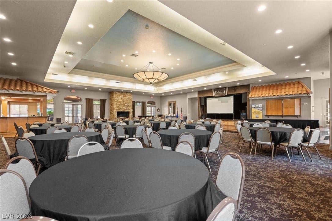 8175 Arville Street, #203, Las Vegas, NV 89139 A spacious clubhouse hall featuring stone-accented fireplace details and tiered architectural ceilings.