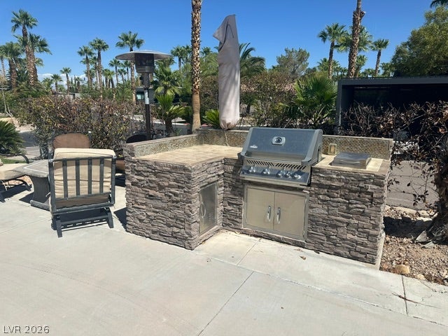 8175 Arville Street, #203, Las Vegas, NV 89139 Stone finishes elevate this built-in outdoor kitchen set against a desert backdrop.
