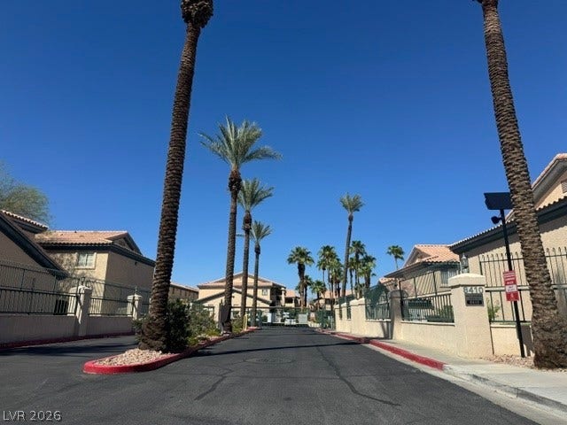 Soaring palm trees frame the gated entry under clear desert skies.