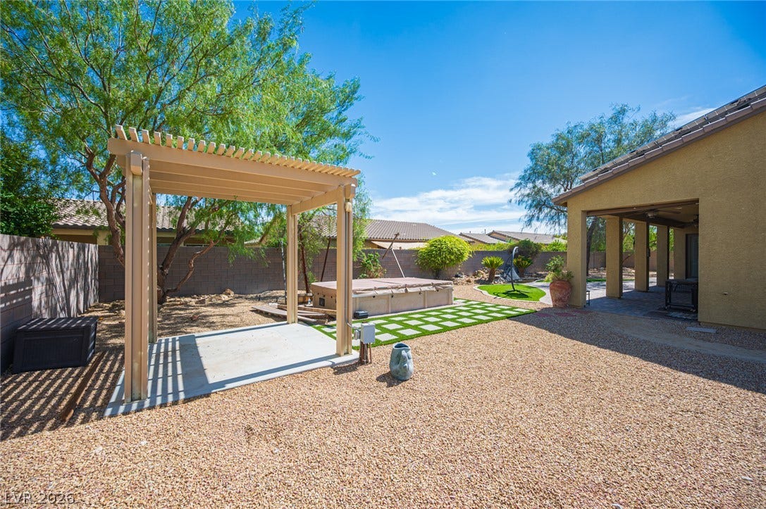 8618 Amber Autumn Street, Las Vegas, NV 89131 A spacious gravel backyard showcases a freestanding pergola alongside a covered patio.