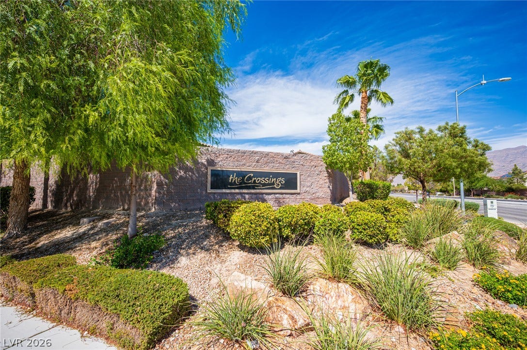 8618 Amber Autumn Street, Las Vegas, NV 89131 Lush landscaping frames the prominent community entrance sign under a clear blue sky.