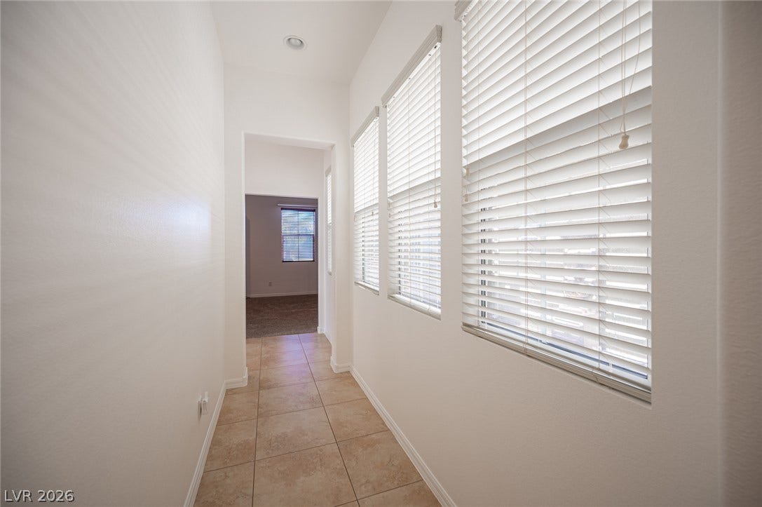 8618 Amber Autumn Street, Las Vegas, NV 89131 A tiled hallway lined with windows leads toward adjacent living spaces.