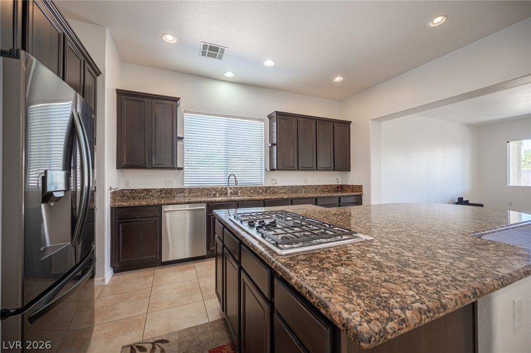 8618 Amber Autumn Street, Las Vegas, NV 89131 Rich dark cabinetry pairs perfectly with granite countertops in this modern open kitchen.