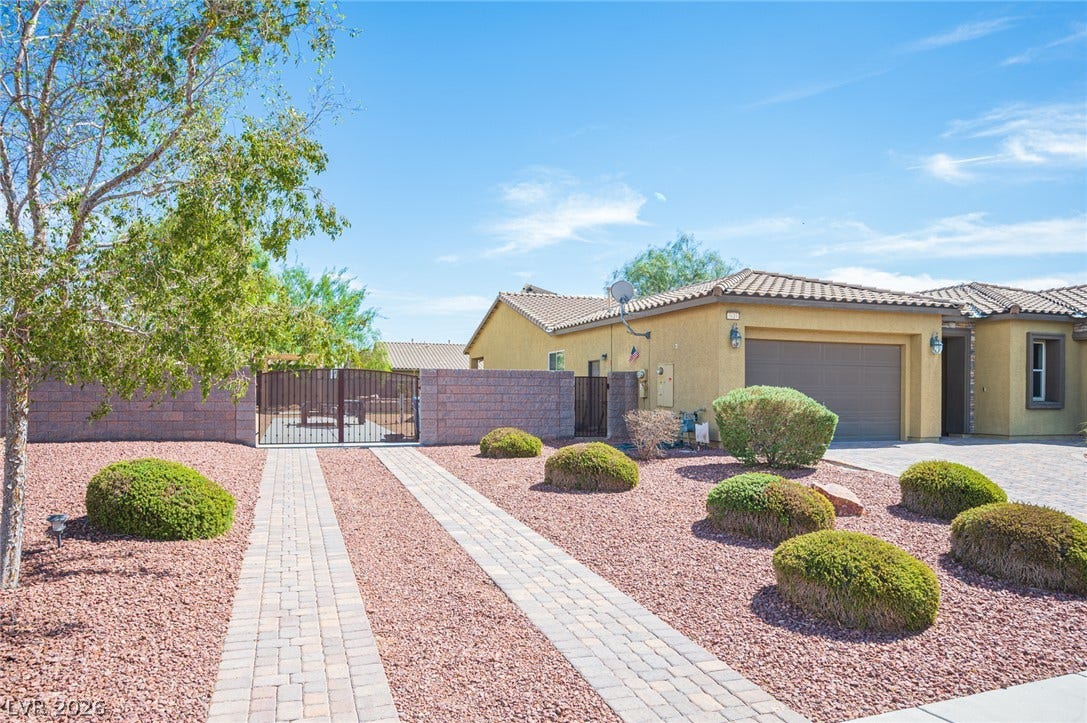 8618 Amber Autumn Street, Las Vegas, NV 89131 Neat paver pathways cross through desert-friendly landscaping toward a gated side yard and double garage.