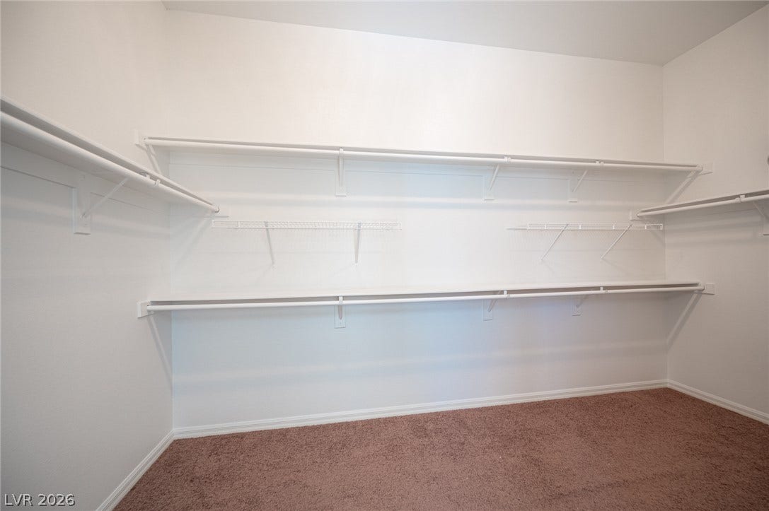 8618 Amber Autumn Street, Las Vegas, NV 89131 Ample built-in shelving and hanging rods maximize storage in this carpeted walk-in closet.
