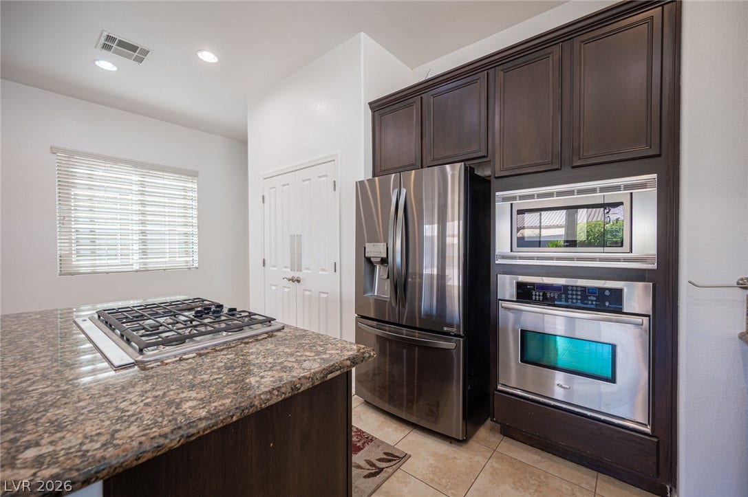 8618 Amber Autumn Street, Las Vegas, NV 89131 Rich dark wood cabinets and stainless steel appliances anchor this modern culinary space.