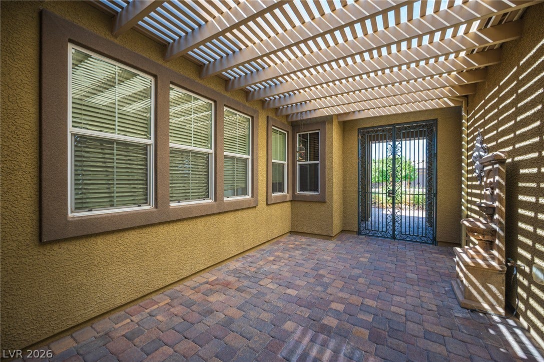 8618 Amber Autumn Street, Las Vegas, NV 89131 An inviting gated courtyard features textured stucco walls, paver flooring, and a shaded pergola structure.