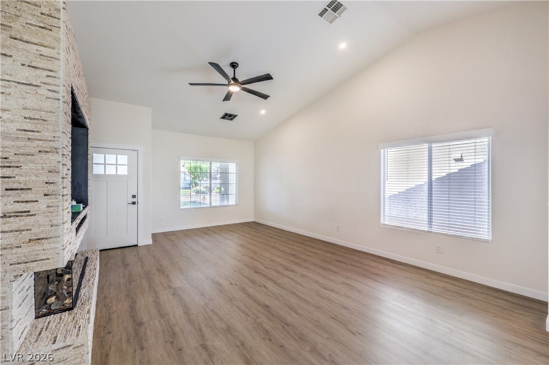 7504 Powder River Court, Las Vegas, NV 89131 Vaulted ceilings and wood-style flooring elevate this comfortable living area anchored by a stone fireplace.