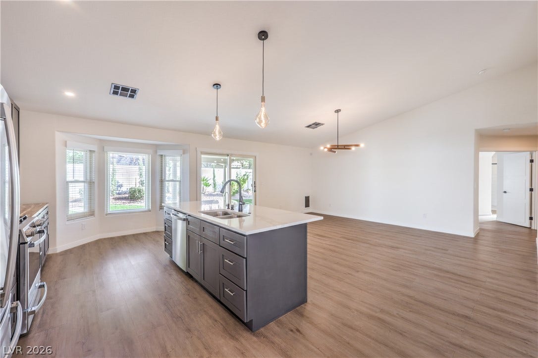 7504 Powder River Court, Las Vegas, NV 89131 Gleaming wood floors anchor a spacious open-concept kitchen and dining area under vaulted ceilings.