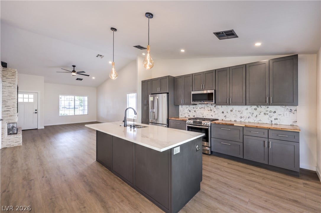 7504 Powder River Court, Las Vegas, NV 89131 Gleaming quartz and butcher block countertops and wood flooring anchor this airy, open-concept kitchen.