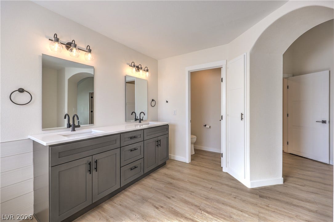7504 Powder River Court, Las Vegas, NV 89131 A spacious double vanity and smooth wood-look flooring anchor this master bathroom layout.