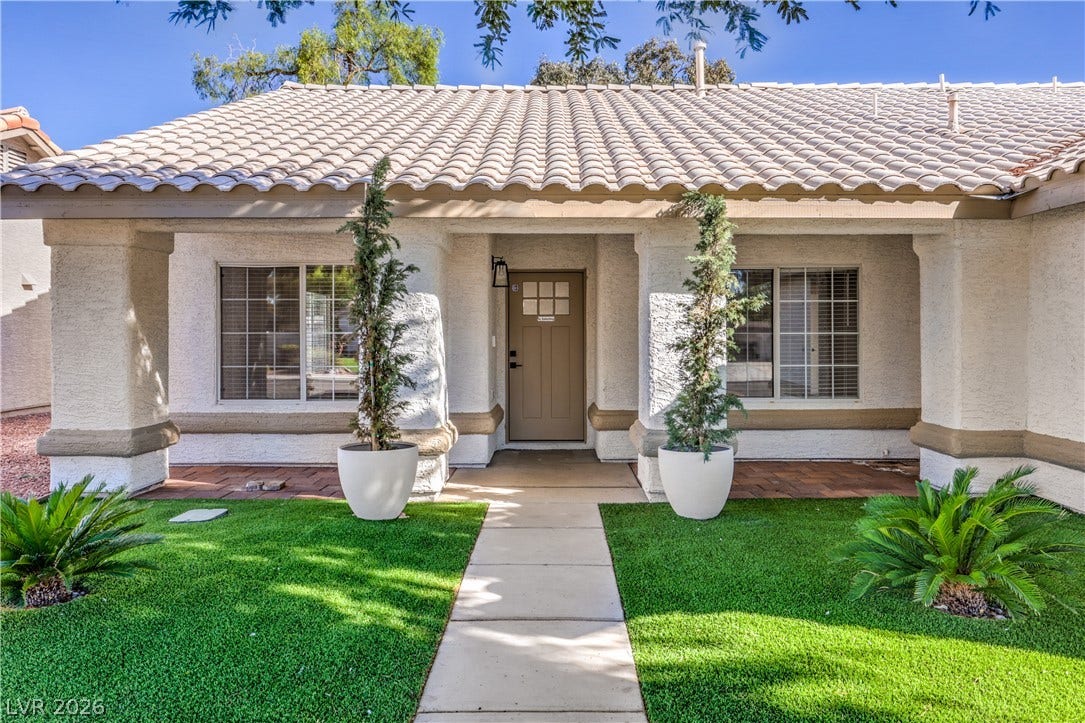 7504 Powder River Court, Las Vegas, NV 89131 A welcoming front porch with classic columns and Spanish tile roofing creates immediate curb appeal.