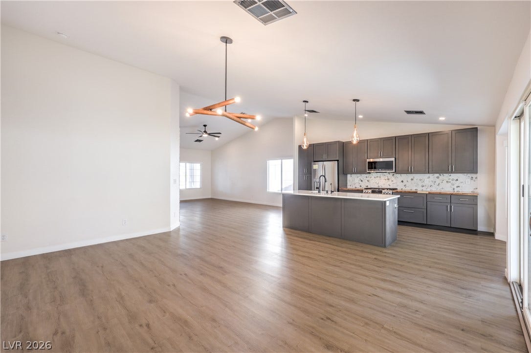 7504 Powder River Court, Las Vegas, NV 89131 Gleaming wood-look floors anchor a modern open kitchen under soaring vaulted ceilings.