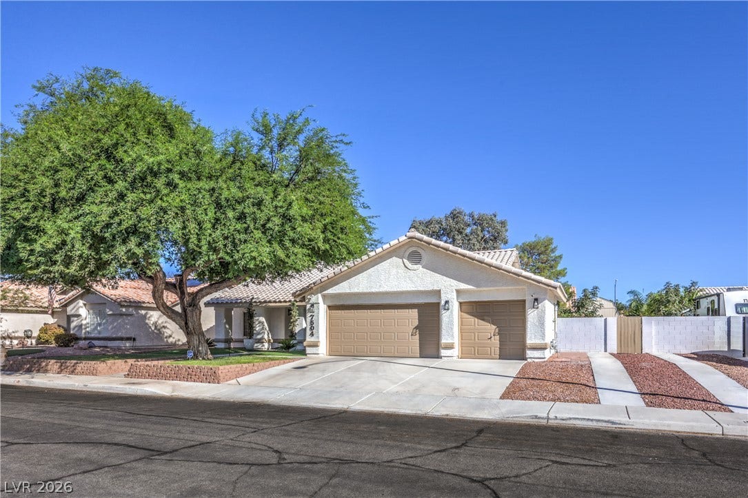 7504 Powder River Court, Las Vegas, NV 89131 A spacious driveway leads to three garage bays alongside low-maintenance landscaping and mature trees.