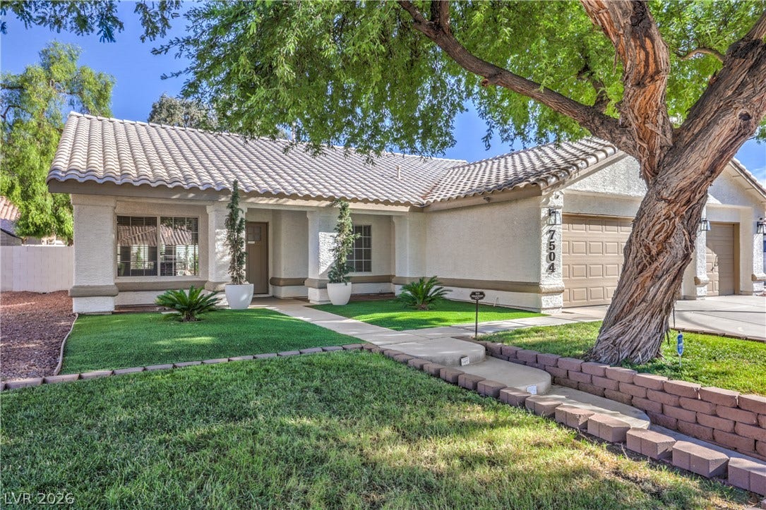 7504 Powder River Court, Las Vegas, NV 89131 Mature trees shade the manicured lawn of this tile-roof residence featuring an attached garage.