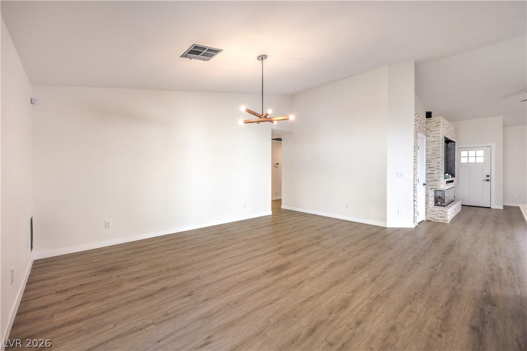 7504 Powder River Court, Las Vegas, NV 89131 Smooth wood-look flooring stretches across a spacious, open living area with clean plaster walls.