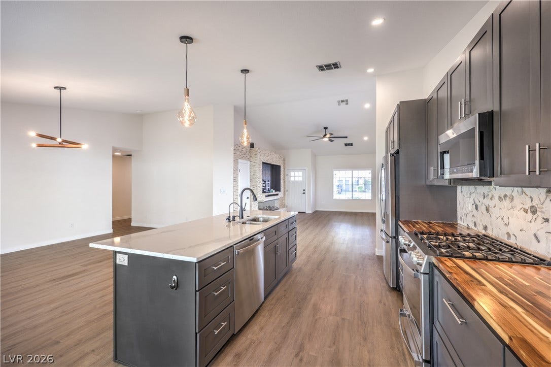 7504 Powder River Court, Las Vegas, NV 89131 Rich wood-look flooring connects a modern kitchen to an airy, open-concept living space.