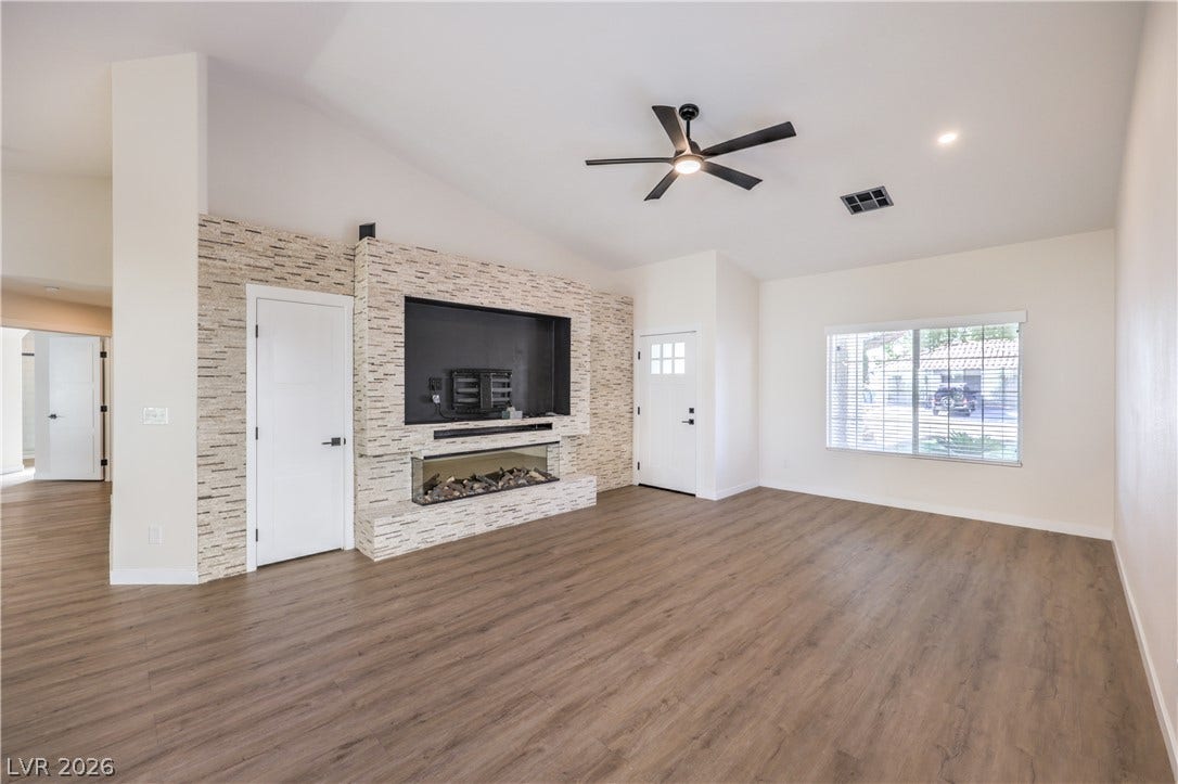 7504 Powder River Court, Las Vegas, NV 89131 An inviting stone-clad fireplace and wood-look flooring ground this airy, open-concept living space.