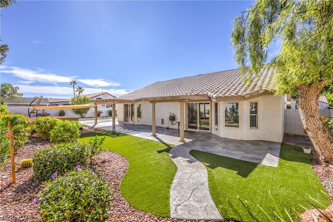 7504 Powder River Court, Las Vegas, NV 89131 A curved concrete path winds through manicured landscaping toward a covered rear patio.