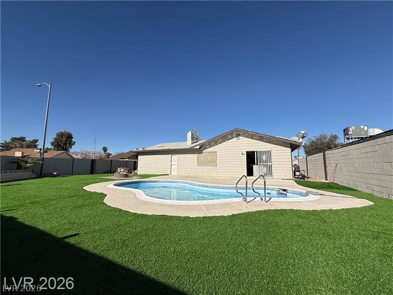 6489 Bugbee Avenue, Las Vegas, NV 89103 An inviting backyard oasis centers around a curved in-ground pool bordered by lush green turf.