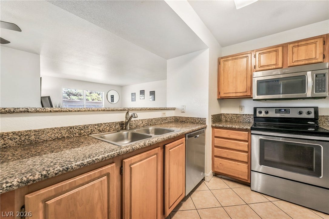 5055 W Hacienda Avenue, #1136, Las Vegas, NV 89118 Polished granite countertops and classic wooden cabinetry define this functional kitchen layout.