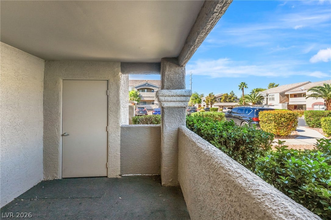 5055 W Hacienda Avenue, #1136, Las Vegas, NV 89118 A private covered patio overlooks the surrounding community landscaping under clear blue skies.