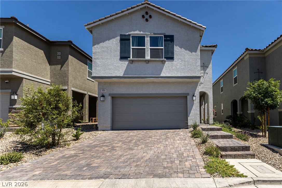 10034 Sir Atlas Court, Las Vegas, NV 89148 A paved driveway leads to a modern stucco home featuring a two-car garage.