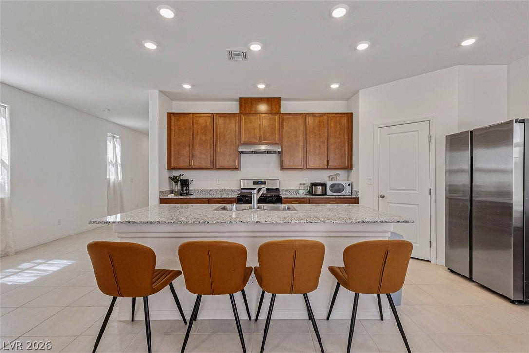 10034 Sir Atlas Court, Las Vegas, NV 89148 Gleaming stone countertops and warm wood cabinetry anchor this modern culinary space.