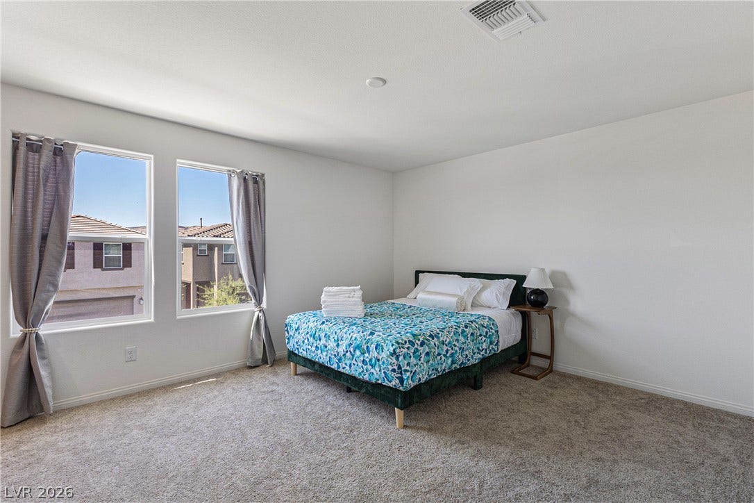 10034 Sir Atlas Court, Las Vegas, NV 89148 A clean-lined bedroom features plush carpeting and multiple windows framing neighborhood views.