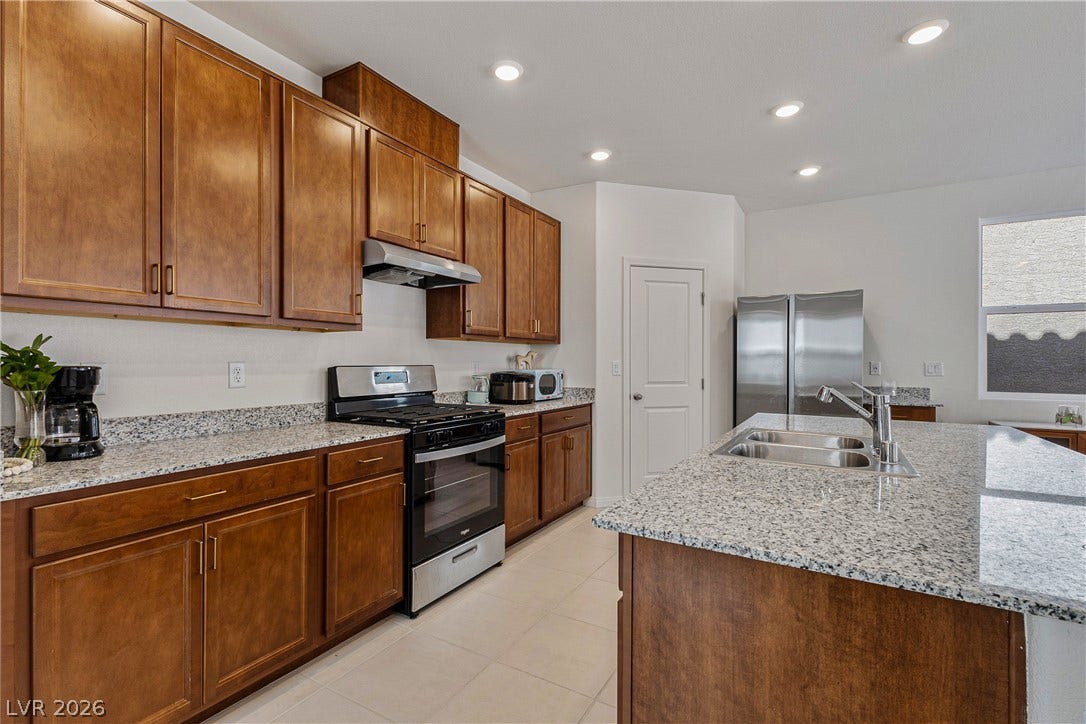 10034 Sir Atlas Court, Las Vegas, NV 89148 Rich wood cabinetry contrasts beautifully with granite countertops in this functional workspace.