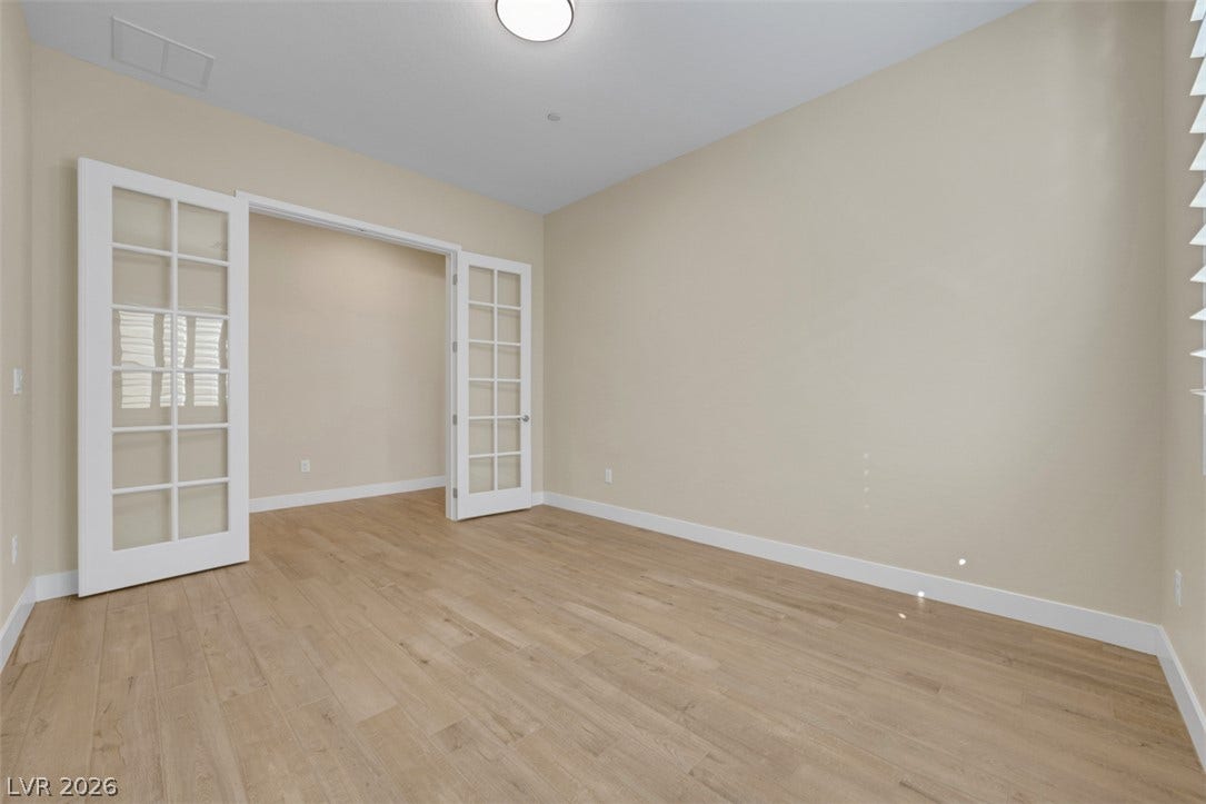 Elegant French doors open into a versatile home office space with light hardwood flooring.