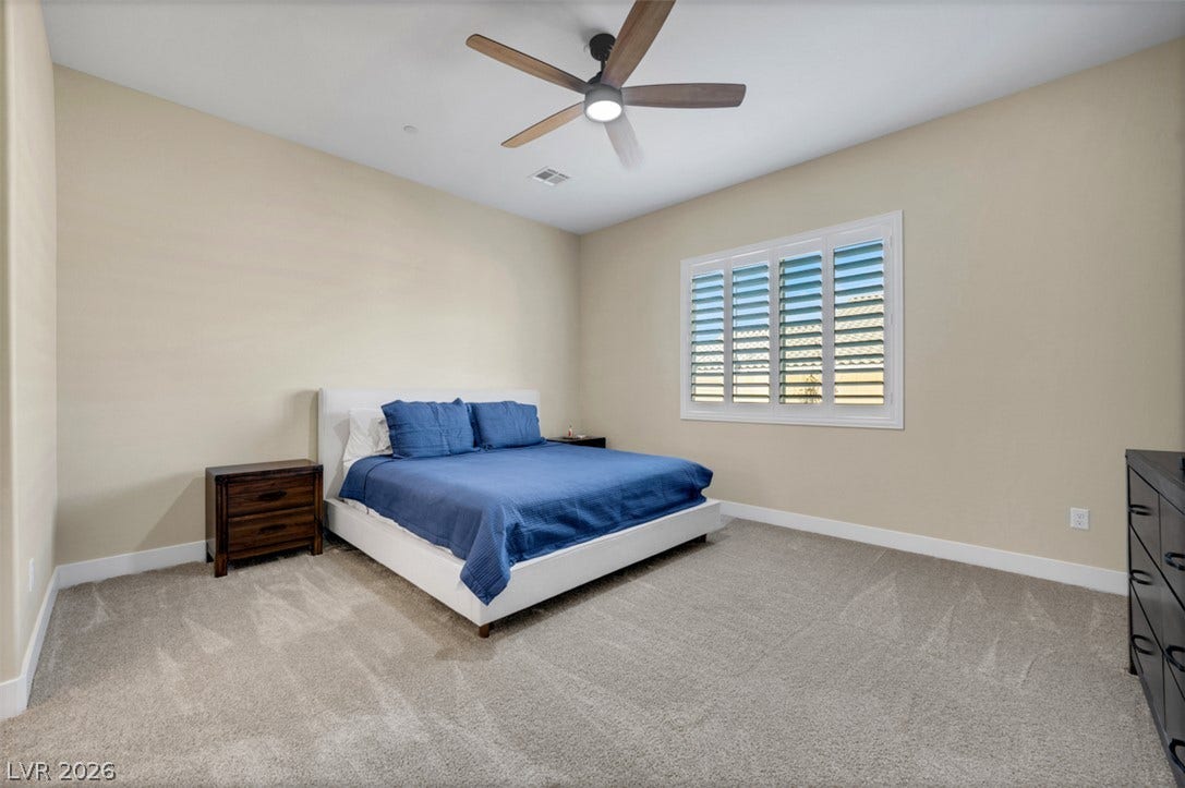 Plush carpeting and plantation shutters define this inviting bedroom space.