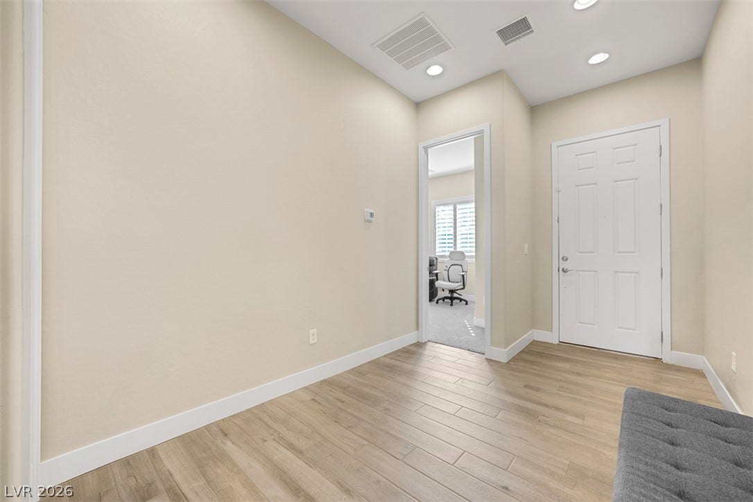 Smooth wood-style flooring and high ceilings with recessed lighting define this welcoming entry space.